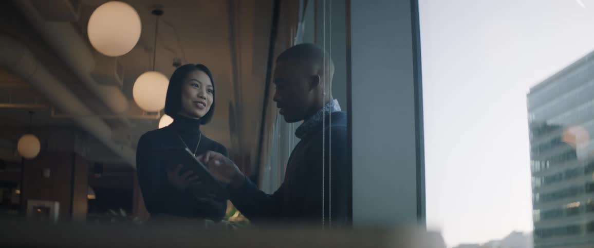 Two coworkers discussing in the office beside the window