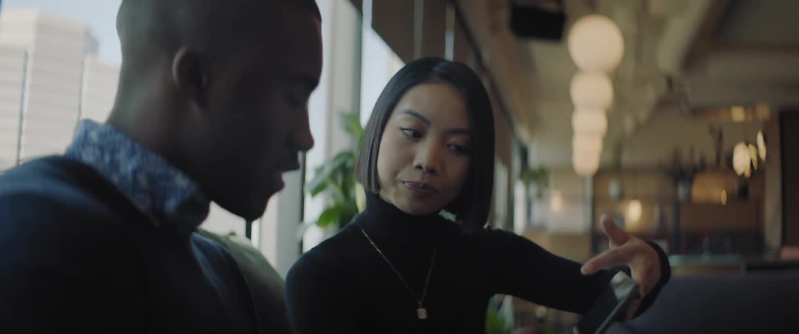 A woman is talking to a man while looking at a tablet