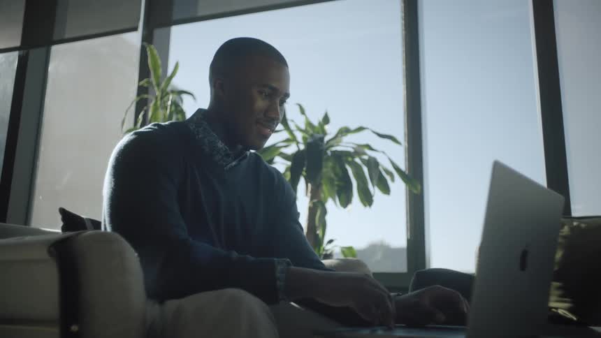Man smiles and nods while viewing laptop
