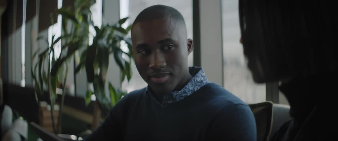 Black man talks to asian woman indoors