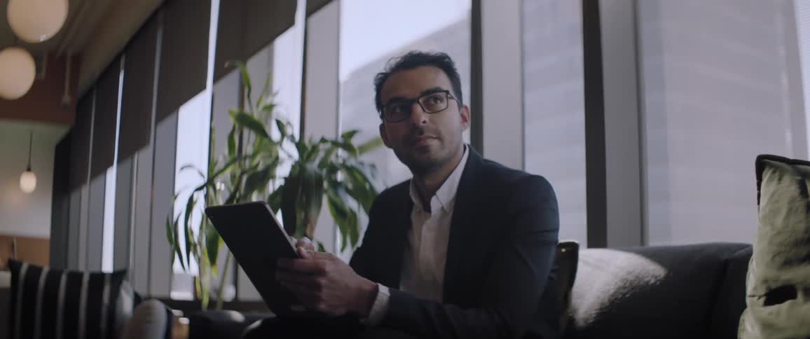 A clip of a man sitting while operating his device and smiling
