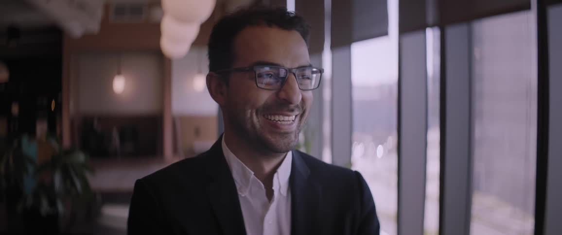 A man posing for a portrait cannot contain his laughter and smiles