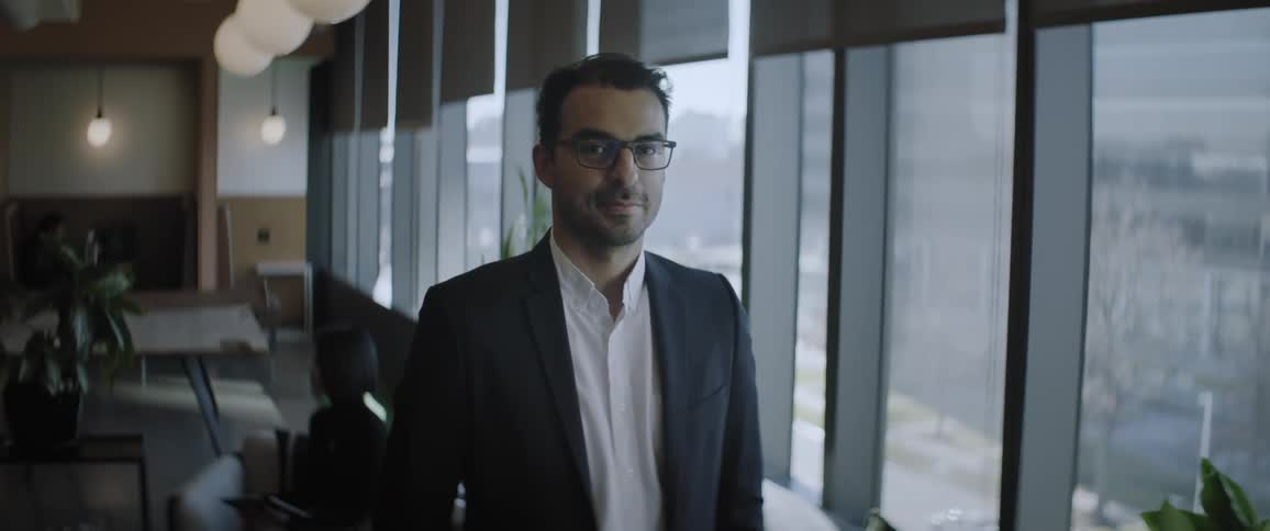 A man on suit smiling and posing in the office