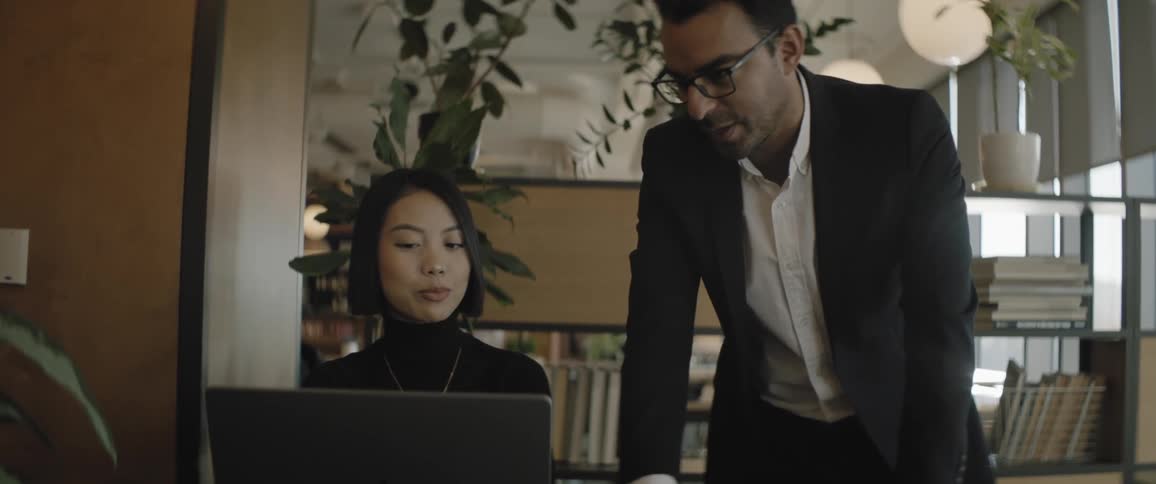 Man and a lady talking inside an office while looking at a laptop