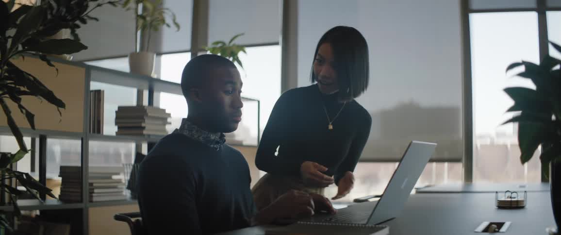 A man and a woman in an office working on a computer