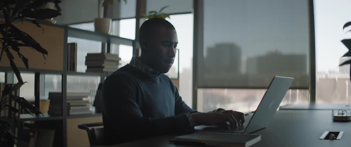 A man is typing on a laptop during his workday