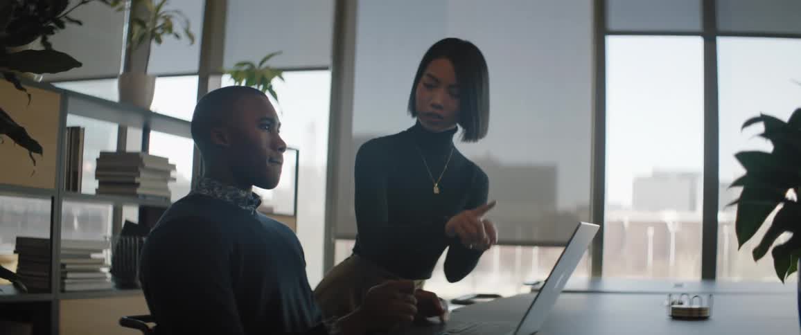 A man and woman talk while looking at a laptop