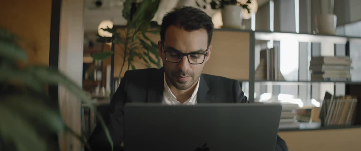 A concentrated man working on a laptop in the office