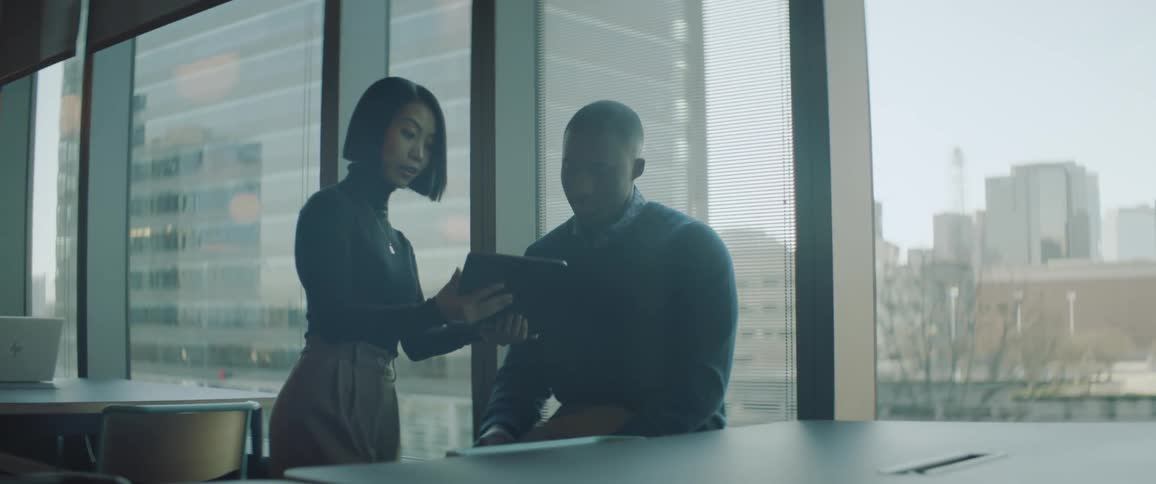 Coworkers talk looking at a tablet in the office