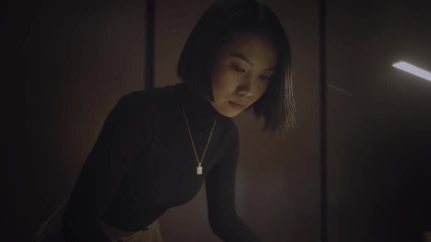 A young woman with a necklace is looking down