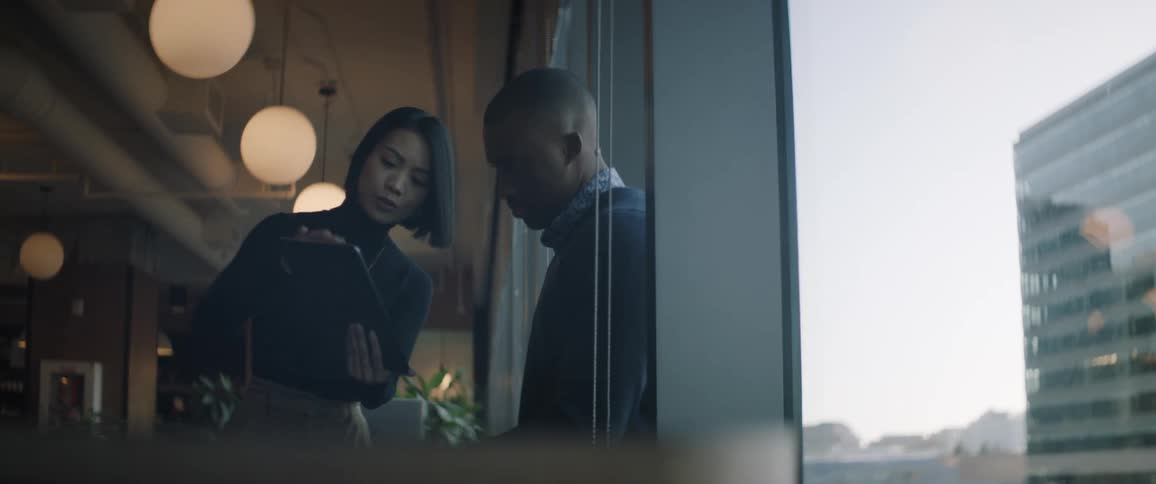 A woman showing something to a man in a tablet