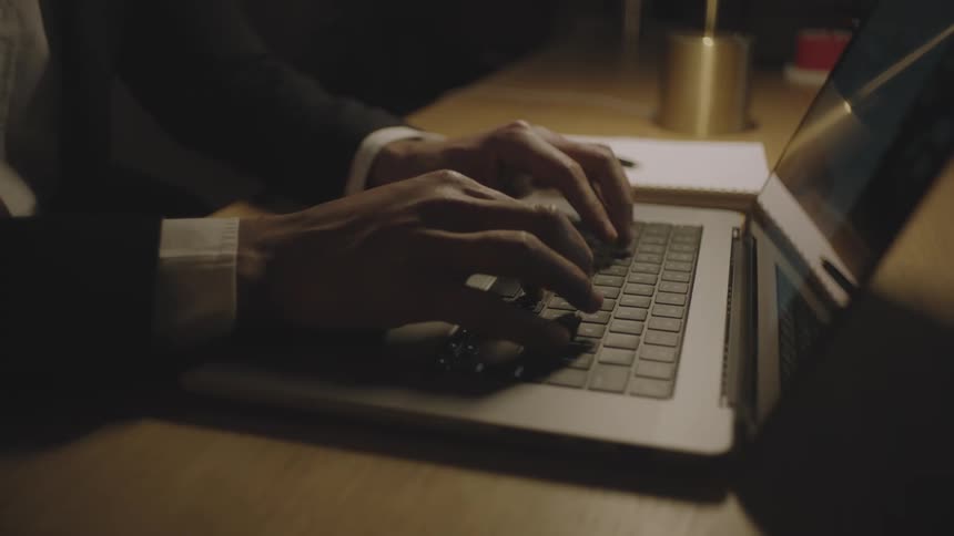 Human hands typing on a laptop that is on the table