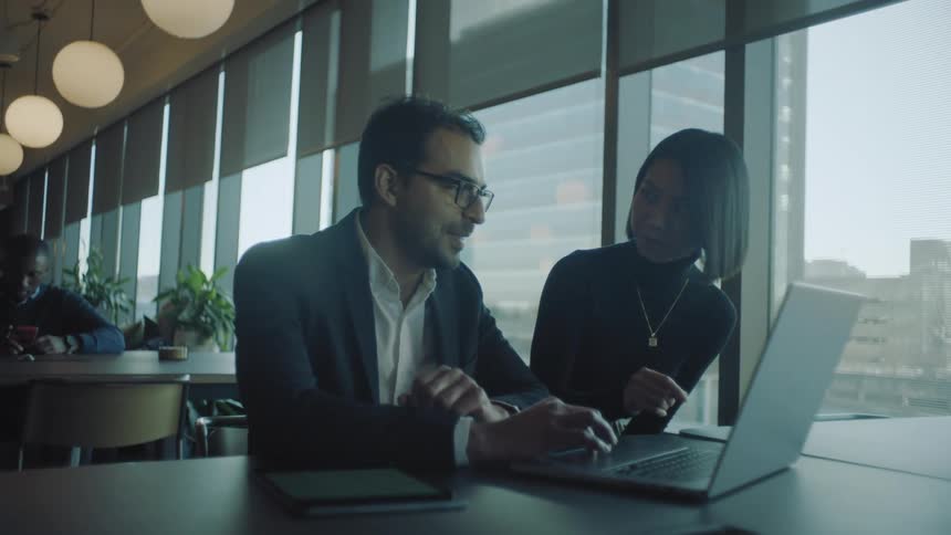 Two coworkers collaborating on a laptop in an office