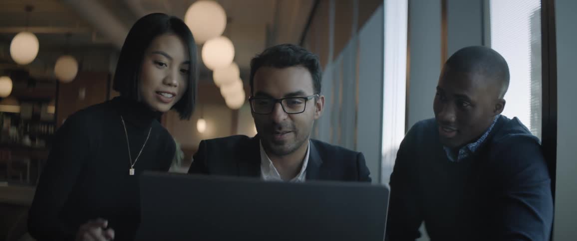 Three coworkers look at a laptop together