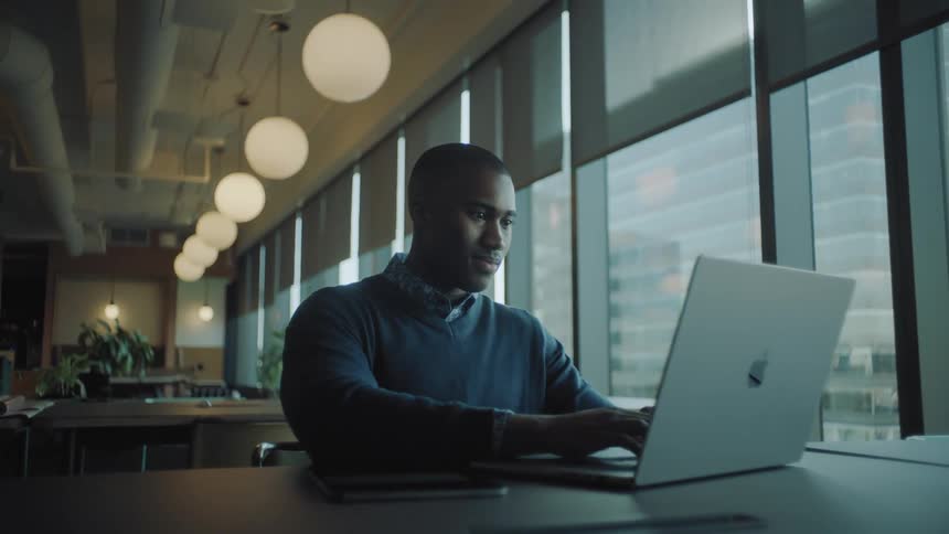 A man sitting and typing on a notebook that is on a table