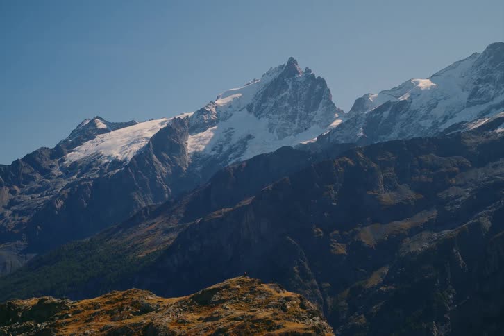 A jagged and rocky mountain peak is covered in snow on a sunny day
