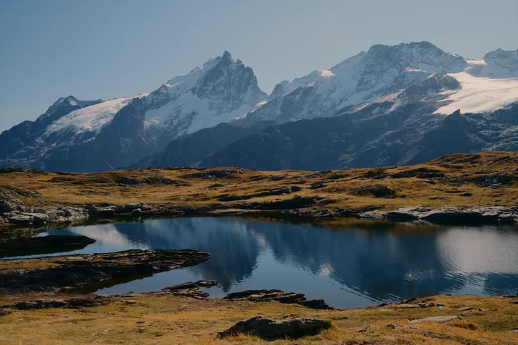 A blue lake near a mountain covered in snow at midday