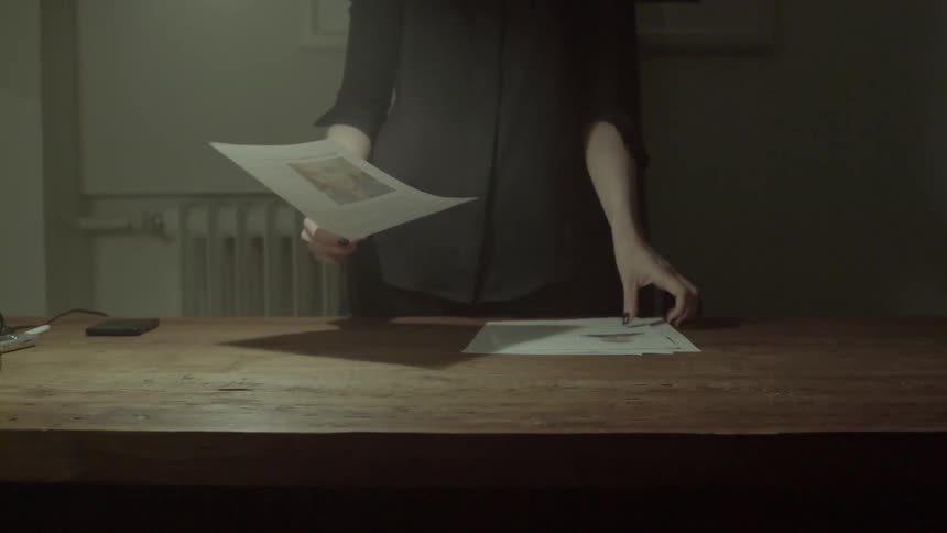 A creative woman reviews various printed sketches and notes to find the best idea.