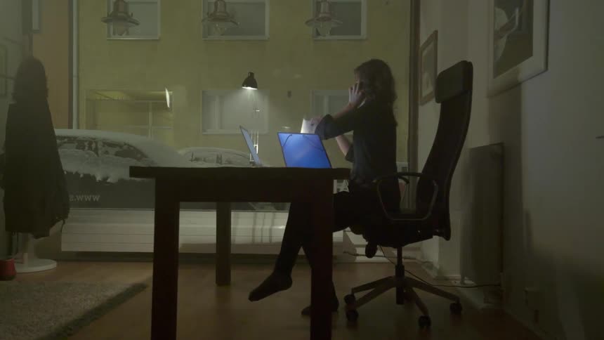 Woman sitting at a desk while on phone takes a piece of paper out of a blue folder