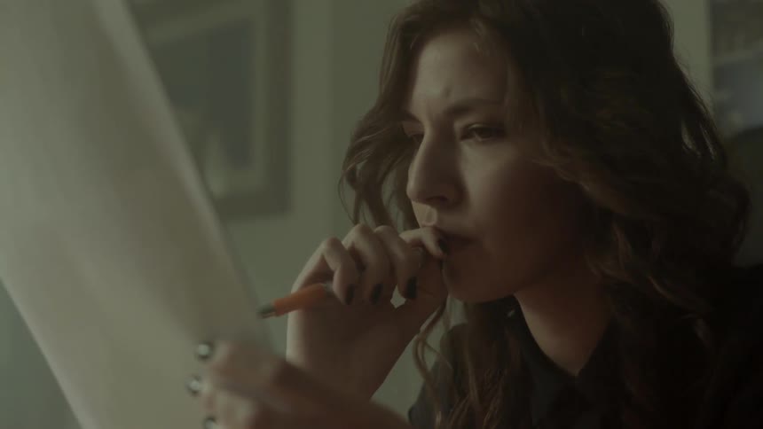A professional woman contemplates her next strategy while looking through several sheets of paper.