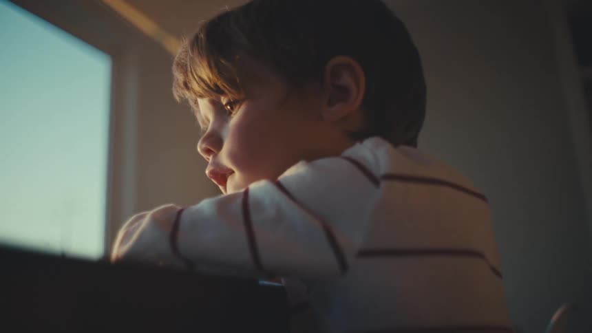 Boy looking out the window from an apartment
