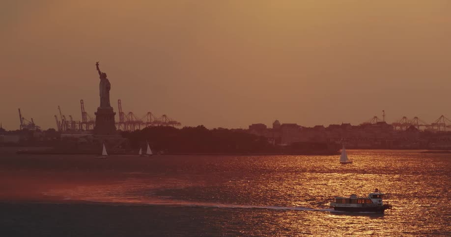 Boats sail in the water around the statue of liberty