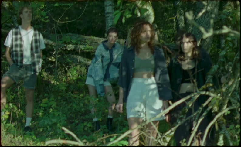 A group of teenagers are standing in the woods