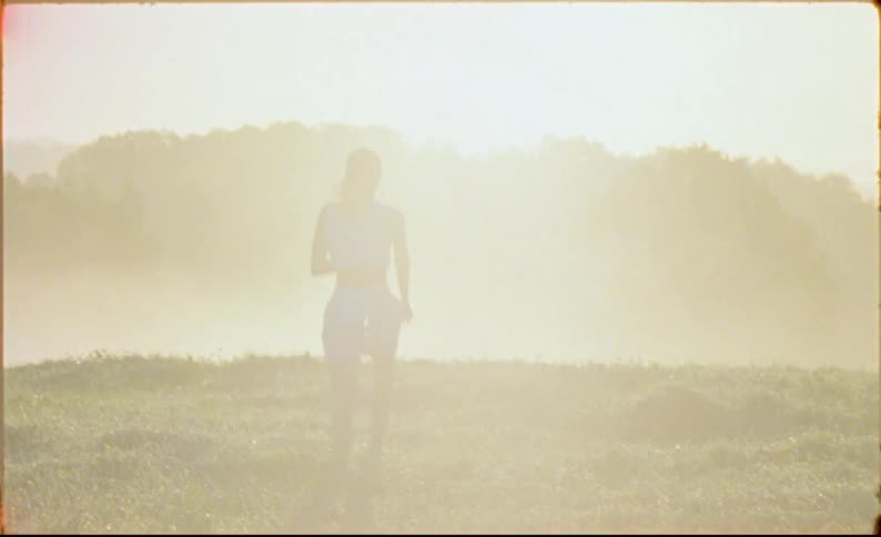 A woman wearing shorts and running in a field with grasses