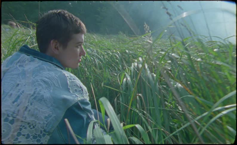 Young woman crouches on a field caught on vintage film