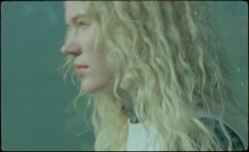 Young blonde woman holding a rock run through smoke in the countryside