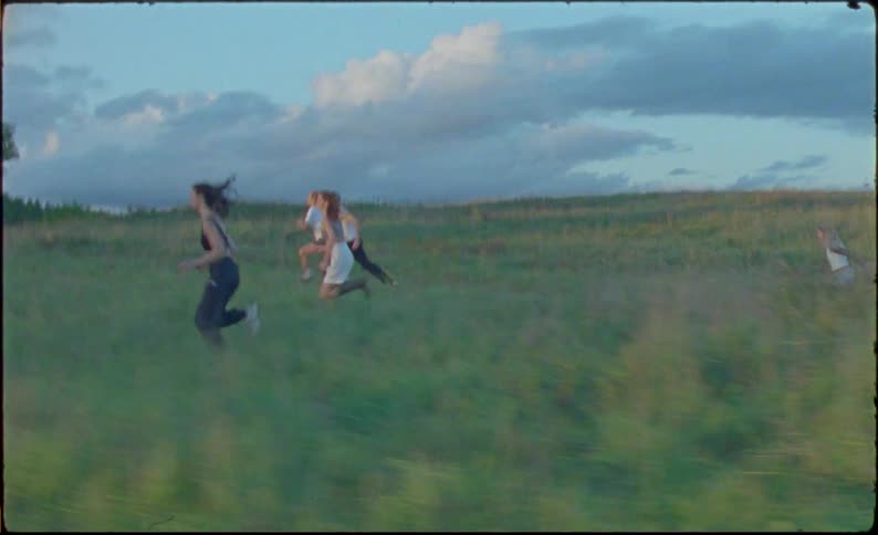 Group of friends running in the countryside caught on vintage film