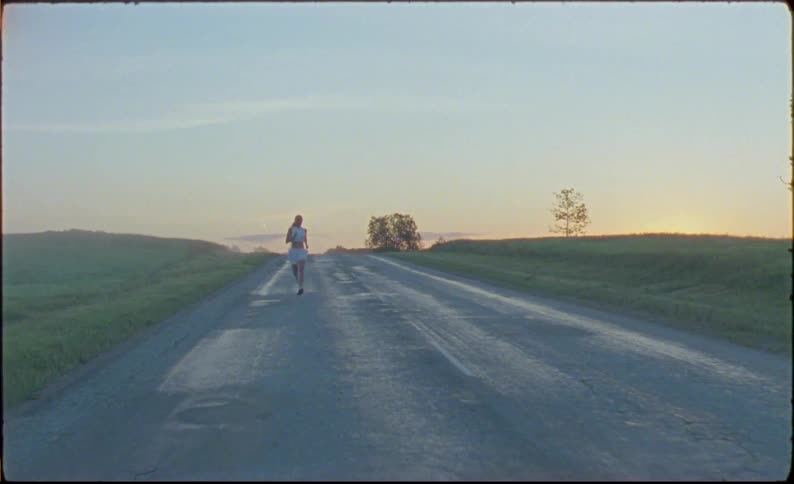 Woman jogs along highway in opposite direction of motor vehicle