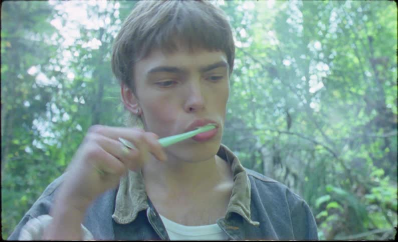 Young man brushes his teeth in the forest