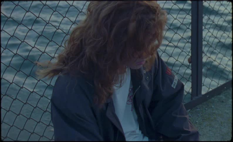 Young woman reclined on a fence selects a candy bar