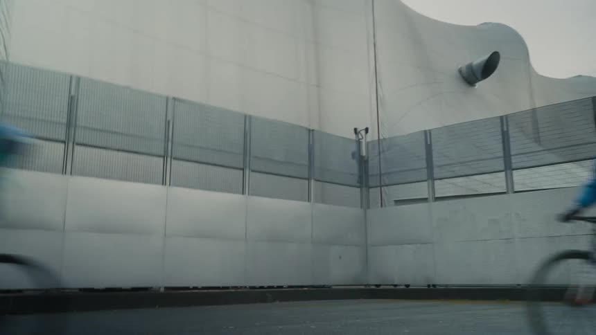 A couple of cyclists riding next to a building