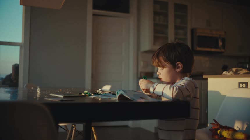 A little boy reading a book and assembling lego pieces