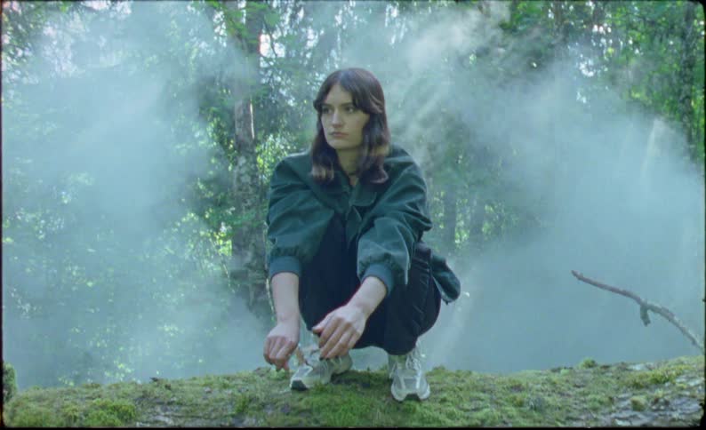 A girl is crouched on the tree log