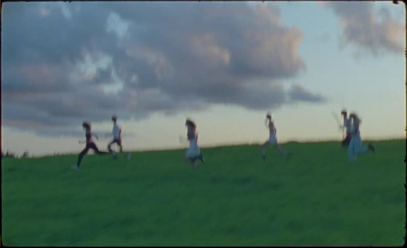 Group of friends running in the countryside caught on vintage film