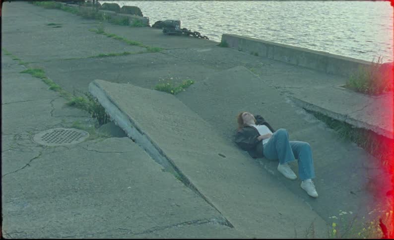 A teenager is laying down by the shore