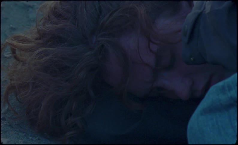 A girl wipes tears from her face on the ground