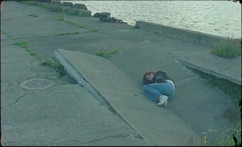 Young  woman lays over a broken concrete slab near a river