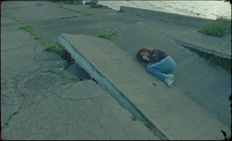 A person lying on the ground on the banks of a river