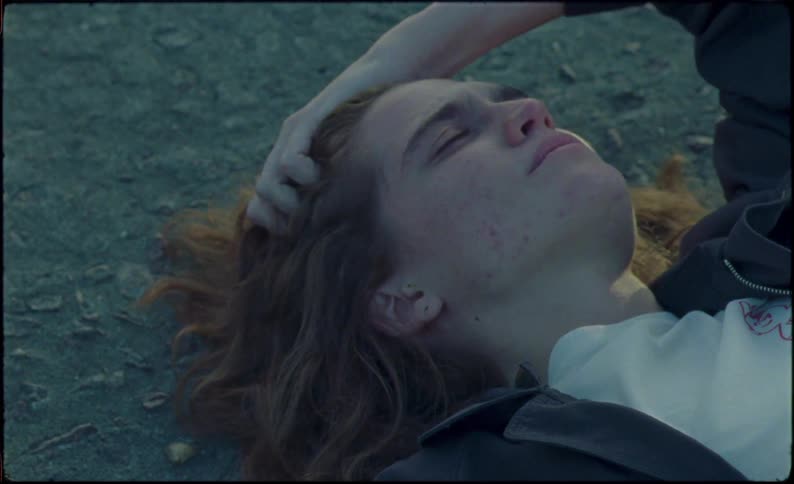 A teenager is laying on the ground