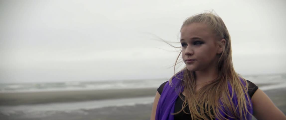 A thoughtful traveler pauses to embrace the wild and windy weather during a coastal escape.