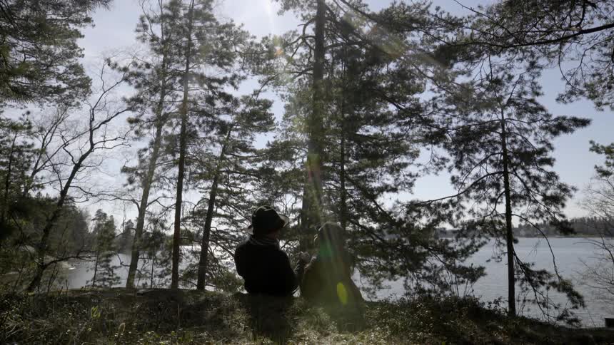 Couple sitting waterside in the wilderness and then lie down on their backs