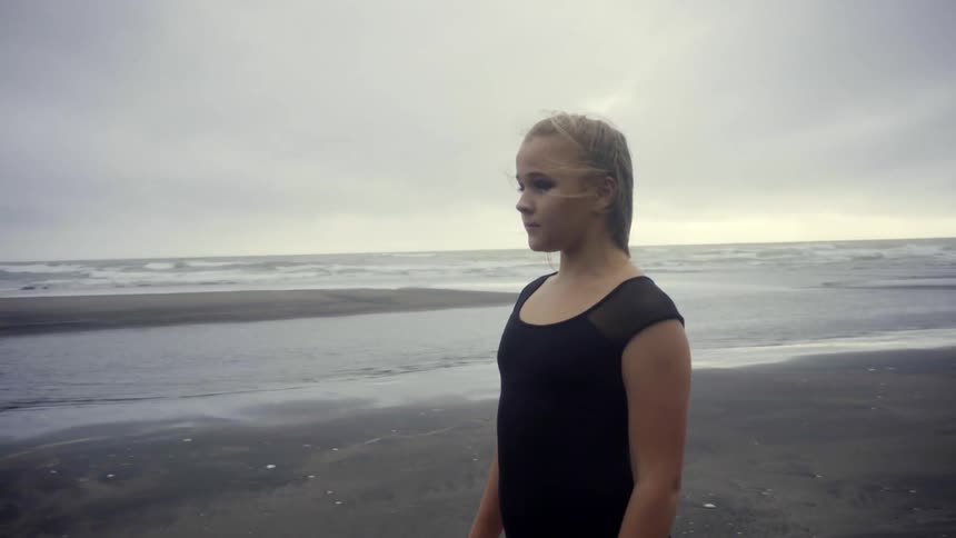 A thoughtful athlete pauses to connect with nature on a moody, overcast beach day.