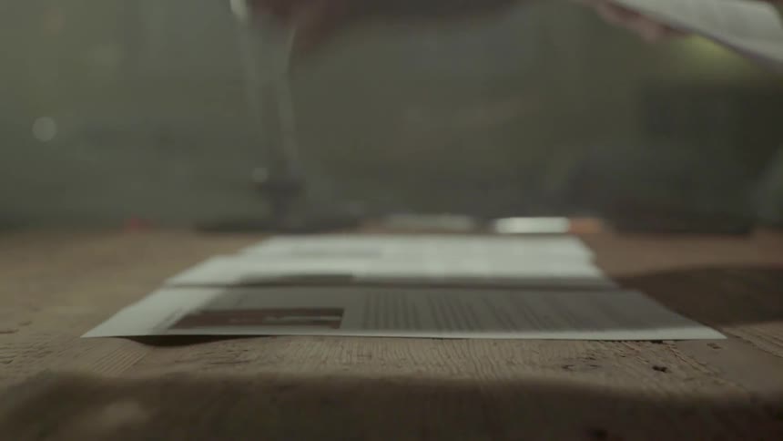 A woman carefully arranges her printed research papers to get a better overview indoors.