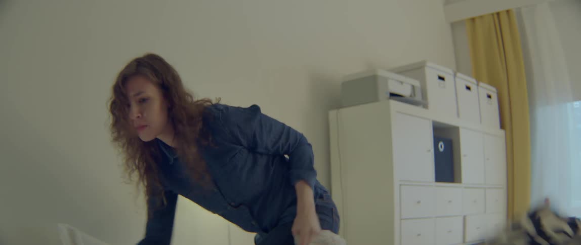 A woman is frantically searching for something in a bedroom