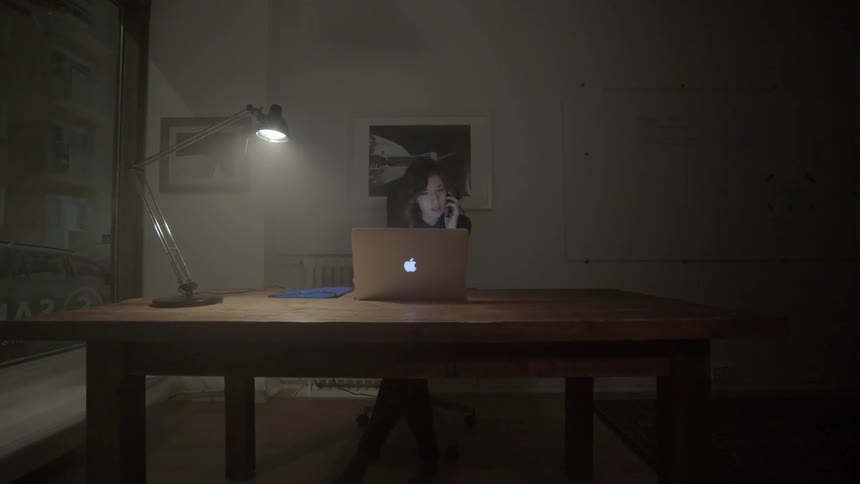 A woman reviews papers under a desktop lamp