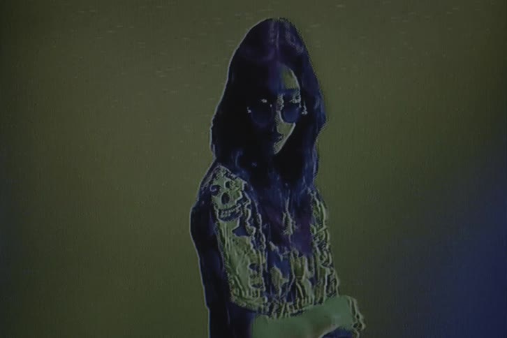 A woman wearing glasses poses for the camera with digital effects applied